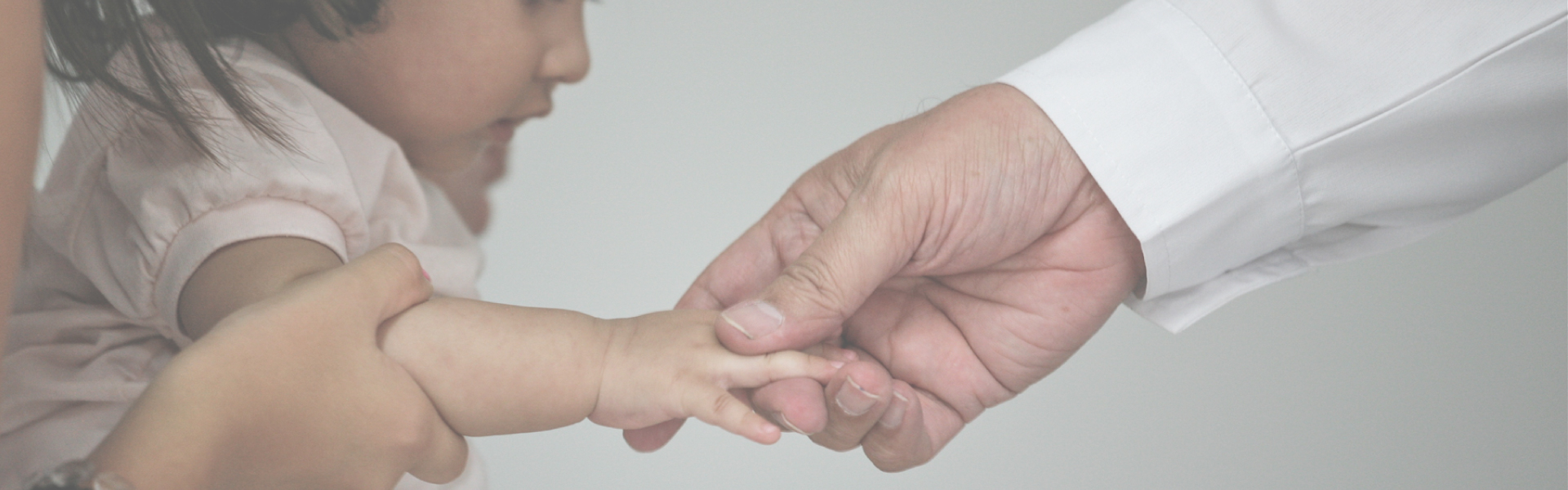 Image of doctor reaching out to a child's hand and touching